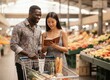 © KIMOG - Happy African American Man Looking at Asian Woman Holding Notebook While Grocery Shopping
