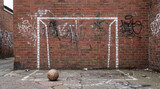 Urban red brick wall featuring a crude chalk drawn goal frame for street football soccer