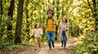 © Muaz - A happy family of four running joyfully through a sun-dappled forest path on a bright autumn day.