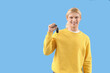 © Pixel-Shot - Young man with car key on blue background