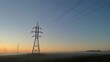 © Olesya - High voltage power transmission lines at sunrise with morning fog, electricity pylons across rural landscape, energy infrastructure, scenic industrial background