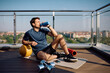 © Drazen - Male athlete drinking water while exercising on terrace.