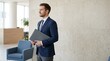 © Bay - Male job candidate standing in modern office holding a briefcase