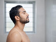 © Someone Cooked Here - Handsome young Indian man enjoying a refreshing shower in side profile in a modern bathroom for grooming and wellness advertising