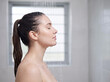 © Someone Cooked Here - Beautiful young white woman enjoying a refreshing shower in side profile in a modern bathroom for skincare and wellness advertising