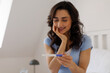 © Home-stock - Happy young woman smiling while looking at pregnancy test, enjoying emotional moment after checking result. Early pregnancy and family planning concept