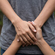 © Novia - Close-up of supportive hands gently holding and comfortingly interlacing with each other, representing love, care, empathy, family unity, emotional connection, trust, and mutual human support.