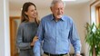 © Thares2020 - A caregiver gently supports an elderly person walking through a warmly lit indoor hallway emphasizing mutual care and companionship