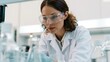 © onlyAW - Female Scientist Examining Samples in Bright Laboratory with Safety Goggles and Lab Coat