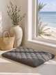 © Vasiliy - Gray floor cushion by a window with a beach view. Minimalist home interior with woven basket and vase. Relaxation and meditation space with ocean background