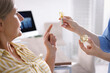 © New Africa - Doctor showing dental implant model to woman in clinic, closeup