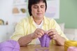 © New Africa - Senior woman knitting with needles at wooden table indoors