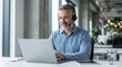© Masque - A smiling and friendly middle aged male call center operator wearing a headset while working.