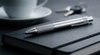 © Masque - A sleek silver pen resting on a closed black notebook in a workspace.