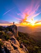 © Siti - A lone figure stands on a rocky outcrop overlooking a serene mountainous landscape at sunset