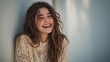 © Gajah - Cheerful young woman with long hair laughing against wall