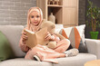 © Pixel-Shot - Little Muslim girl in hijab with teddy bear reading book at home
