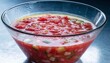 © Mehwish - A clear glass bowl of chilled tomato gazpacho with diced vegetables and condensation suits summer recipe features, restaurant menus, and healthy eating campaigns.