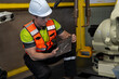 © Nassorn - Industrial Robot Technician: A male technician in a hard hat and safety vest supervises an industrial robotic arm in a factory setting, emphasizing precision engineering and automation.
