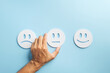 © sorapop - Feedback concept, customer choosing neutral face for satisfaction survey, representing service experience review with hand selecting emoticon face on blue background