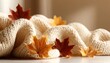 © Ilja - Cozy autumn aesthetic with knitted wool texture background decorated with fallen golden leaves.