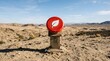 © Huzaifa - A bright red circular sign featuring a white leaf icon sits atop a weathered metal stand in the arid desert