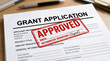 © mraual24 - A printed grant application form features a bold red ink stamp indicating official approved status