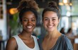 © Betto - Two smiling diverse female entrepreneurs looking at the camera in a modern office