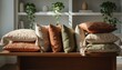 © Olga Gorkun - Collection of textured decorative throw pillows in earthy tones of orange green and cream rests on a wooden table before white shelves