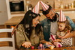 © La Famiglia - Family celebrating daughter's birthday with bubbles and party hats