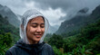 © Rendara Studio - Serene young woman in rain poncho smiling in lush misty green canyon