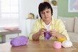 © New Africa - Senior woman knitting with needles at wooden table indoors, space for text