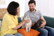 © New Africa - Couple with their cute cats on sofa at home