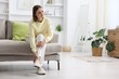 © New Africa - Woman suffering from leg pain on sofa at home, space for text