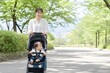 © Muu - 公園でベビーカーを押す若いお母さん