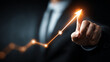 © Subin - A businessman pointing at a glowing graph indicating upward growth and success in a dark background.