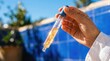 © soem - A person holds a dropper filled with golden liquid against a blue tiled pool. The person is wearing a white shirt and the liquid appears to contain gold flakes.