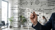 © Brokkk - Professional outlining a project management plan, workflow, and task assignments on a transparent glass board in a modern office setting.