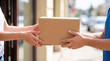 © remake - Courier delivers a cardboard parcel to a customer at the doorstep. Package handover for a delivery service. Online shopping order received at home from a shipping and mail postal carrier.