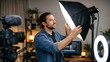 © ImageThink - Man adjusting professional softbox light for video production setup with camera and ring light
