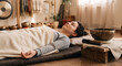 © Martarina - Young woman lying down and relaxing during sound healing therapy session with Tibetan singing bowls