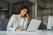 © Stock 4 You - Young Indian woman manager ceo using cell phone mobile, laptop for business call. Smiling Latin female businesswoman holding smartphone in office, talking with client, doing professional consultation
