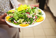 © Samir - Fresh mixed green salad carried by a guest during a catered event. Healthy meal served at a buffet, highlighting authentic hospitality, restaurant service and customer dining experience.