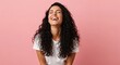 © Network Stock - Woman with long curly dark hair laughing joyfully against a plain pink studio background