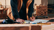 © peopleimages.com - Person, hands and carpenter writing with documents in warehouse for wood stock or lumber production. Carpentry, artisan or schedule with paperwork for furniture distribution or inventory in workshop