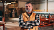 © peopleimages.com - Carpentry, portrait and man in factory with arms crossed, handyman or pride in manufacturing industry. Smile, ambition or mature artisan with about us, production career or confidence in woodworking.