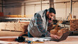 © peopleimages.com - Carpentry, phone call and man on laptop in workshop for planning, schedule or design quote. Warehouse, male person or carpenter with technology for woodwork or furniture production with paperwork