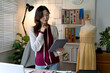 © sabthai - Standing Designer Browses Fabric Options Using Tablet In Studio
