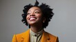 © BABEKU - Joyful woman looking upward curly hair yellow blazer studio portrait