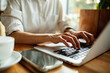 © Marko Geber - Hands typing on laptop in coffee shop